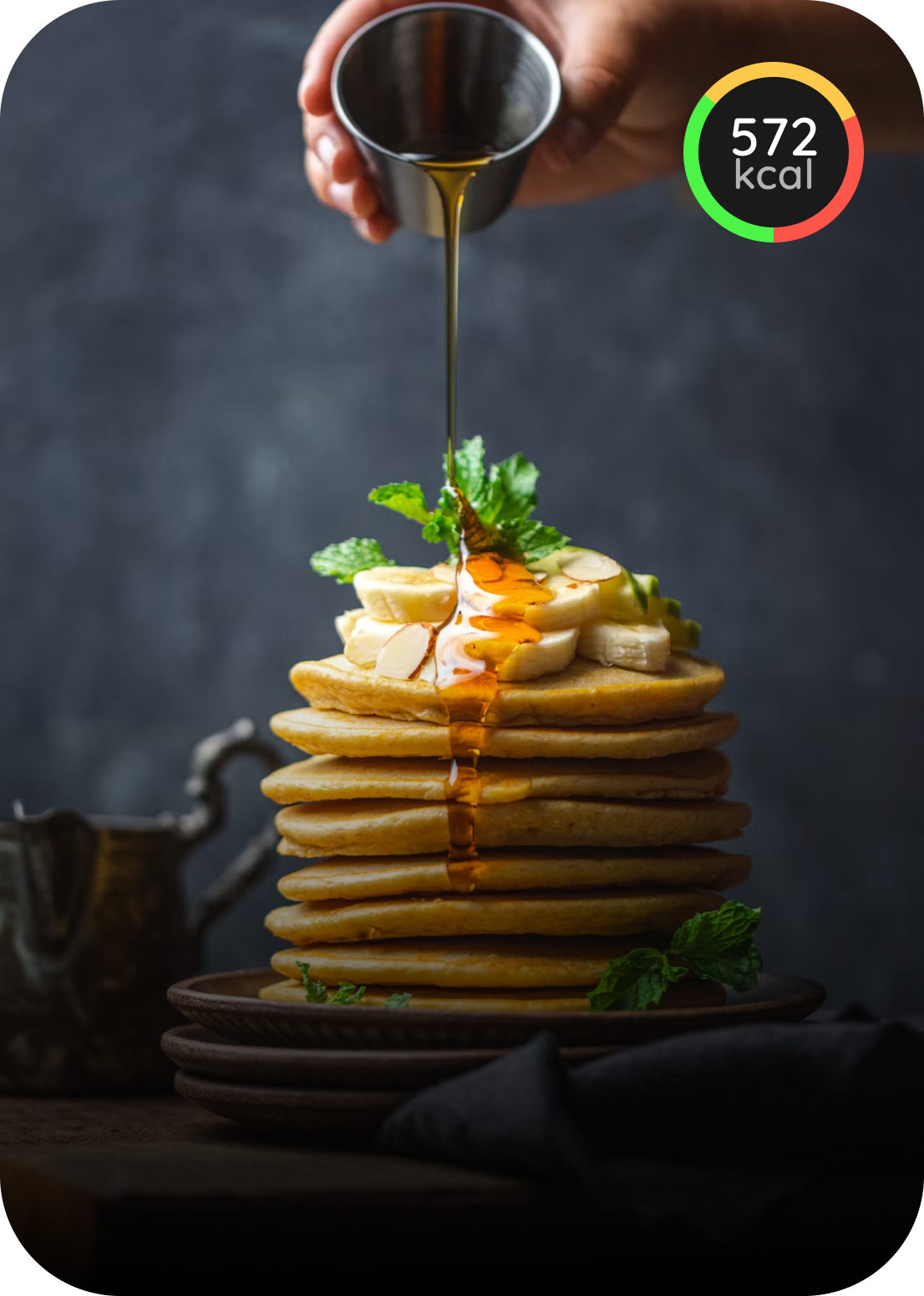 Stack of pancakes topped with banana, mint, and syrup